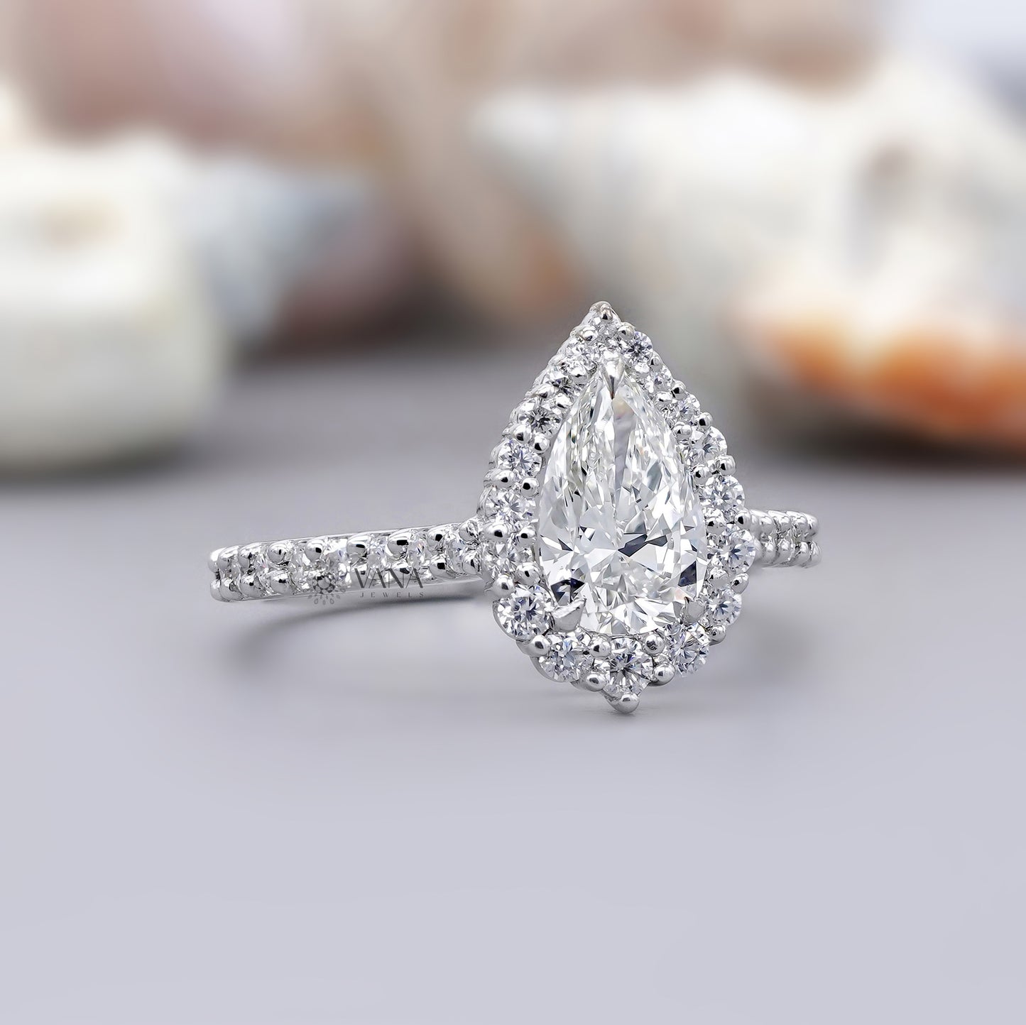White gold halo engagement ring featuring pear shaped moissanite center