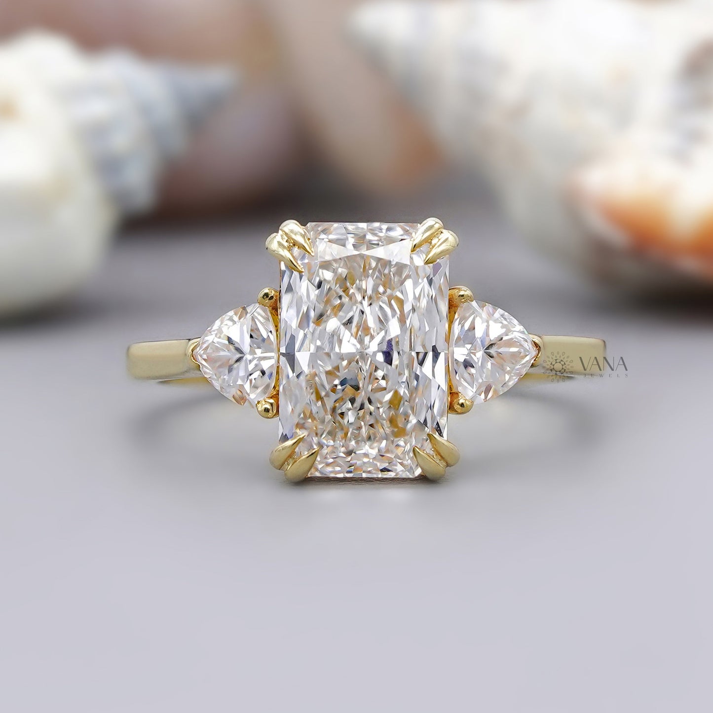 Radiant cut moissanite engagement ring with trillion cut side stones in yellow gold