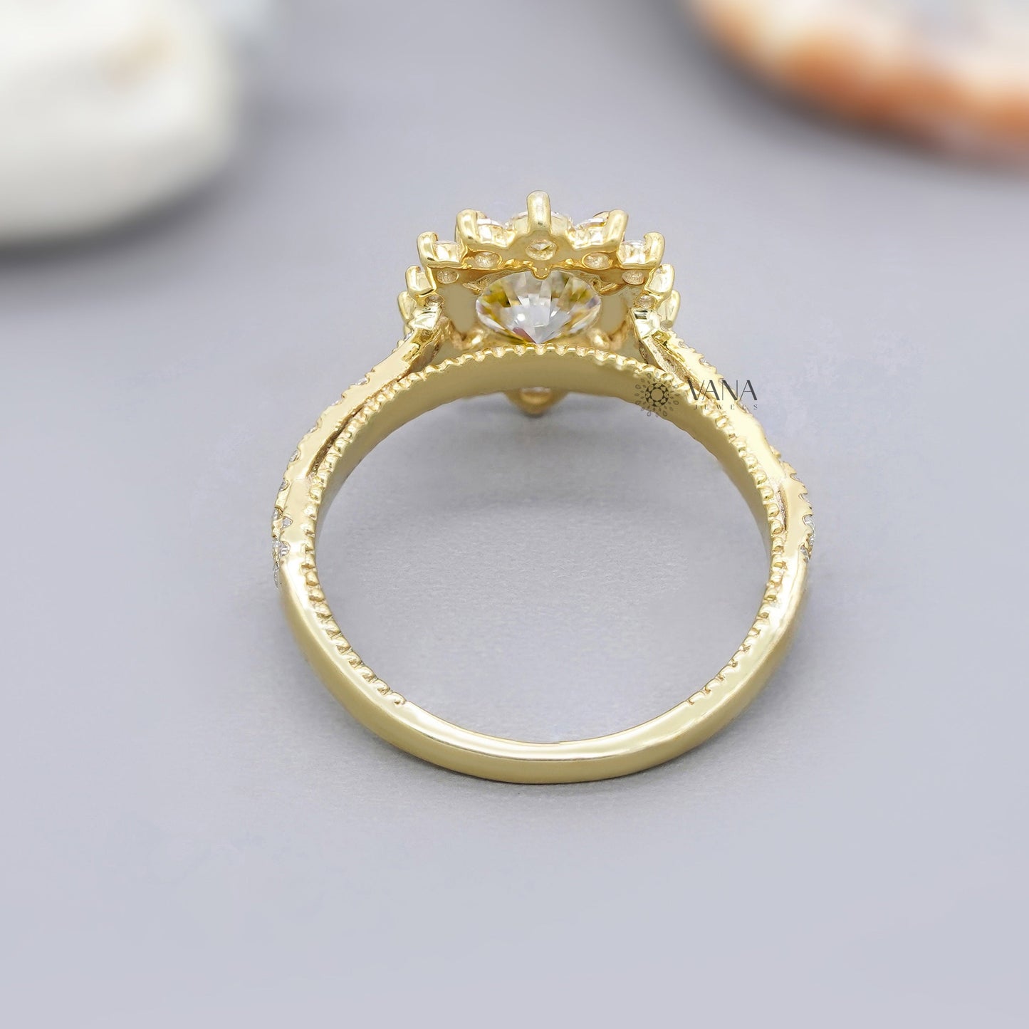 Gold ring with intricate design on a gray surface