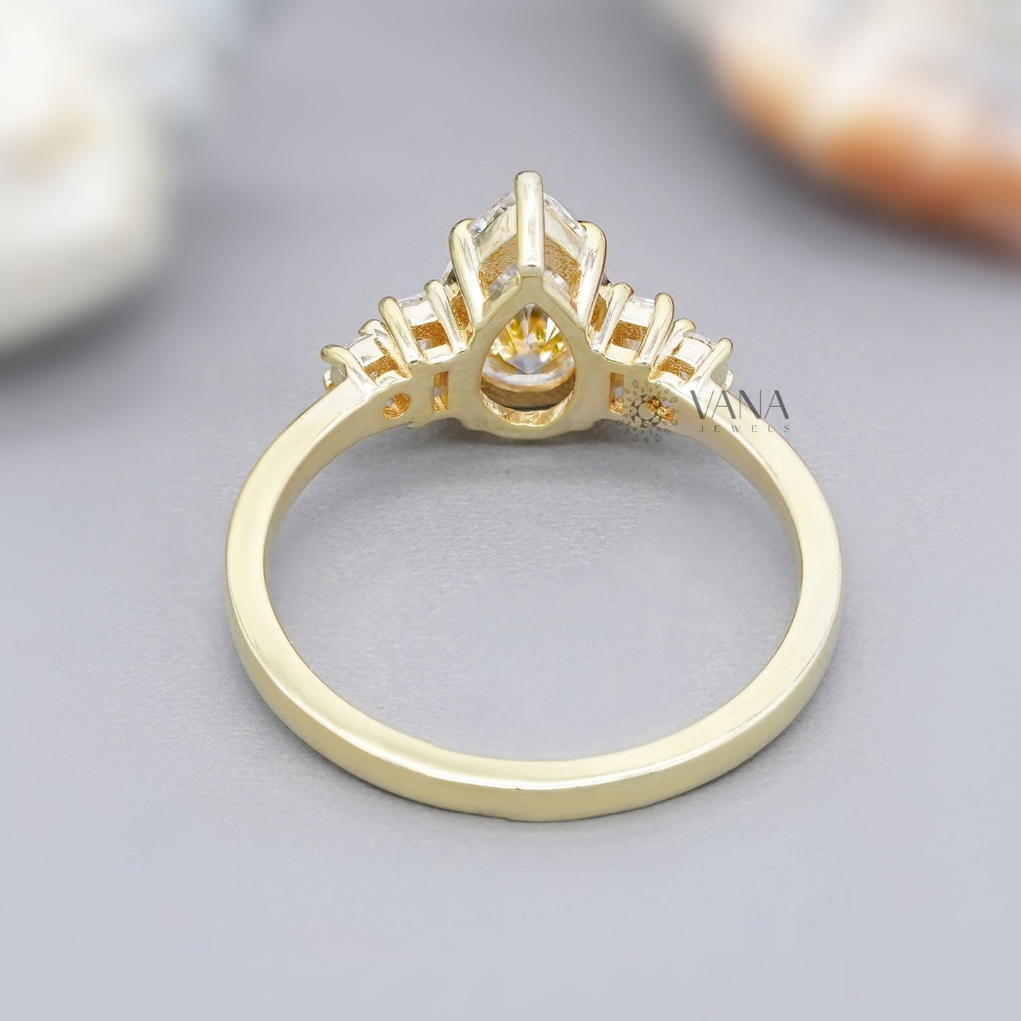 Pear moissanite ring in 14K yellow gold with side baguettes