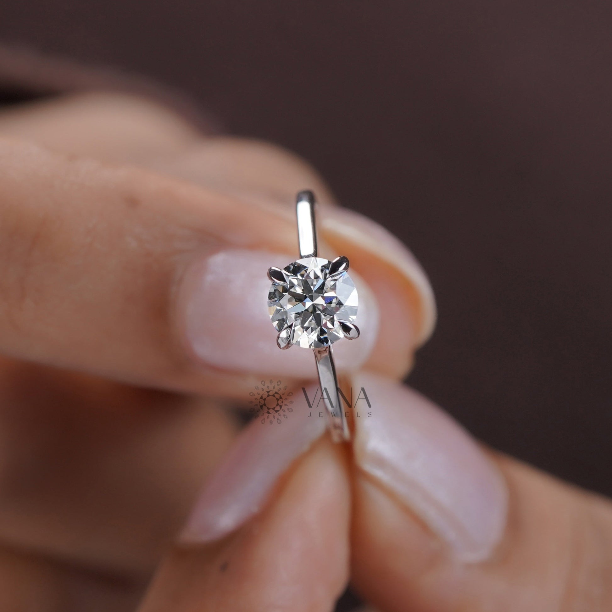 Close-up of a hand holding a diamond ring with a blurred background