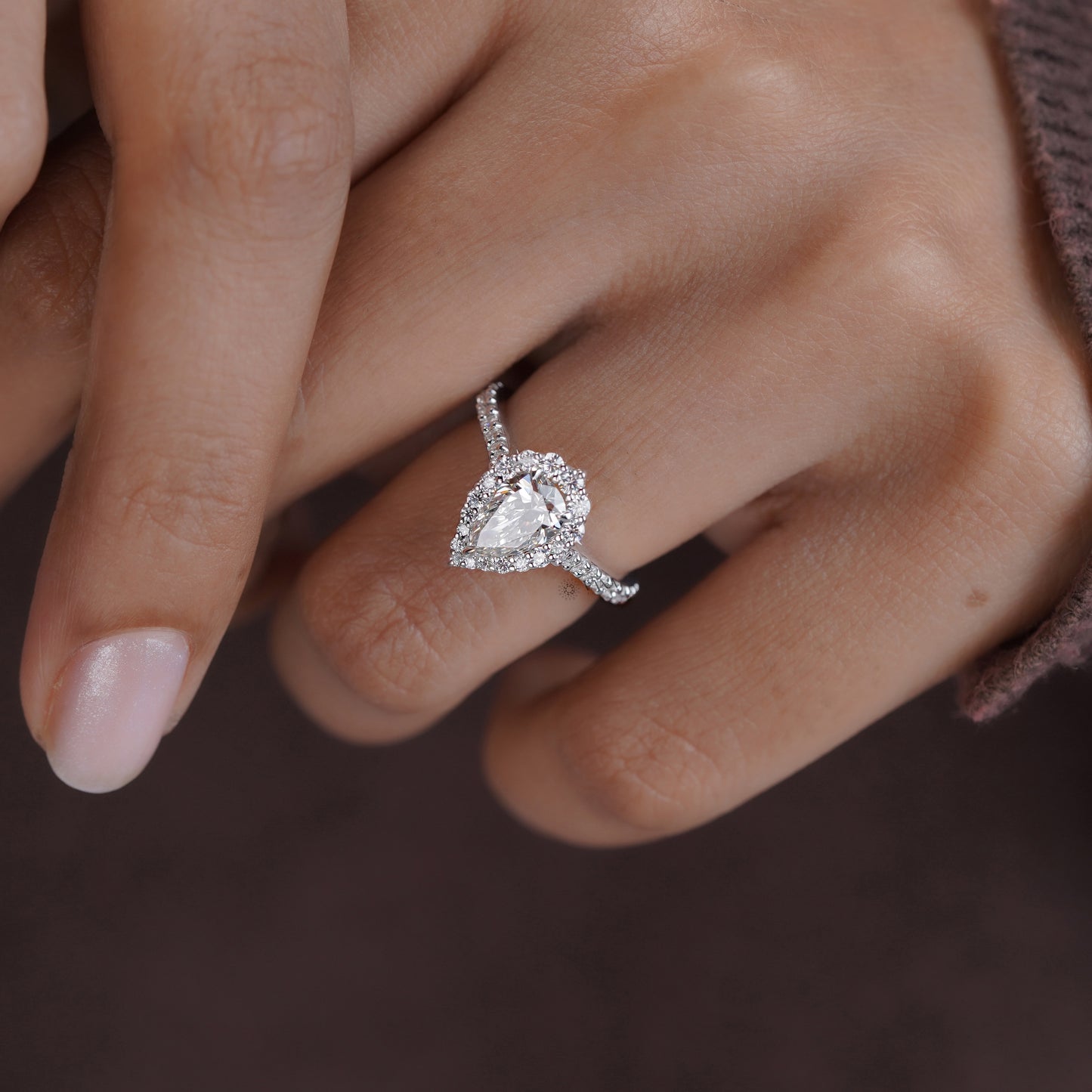 Side view of pear cut moissanite halo ring with brilliant pave band