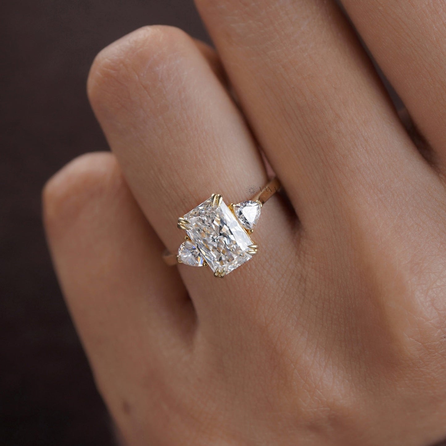 Three-stone moissanite ring with radiant center and double claw prongs in a classic setting