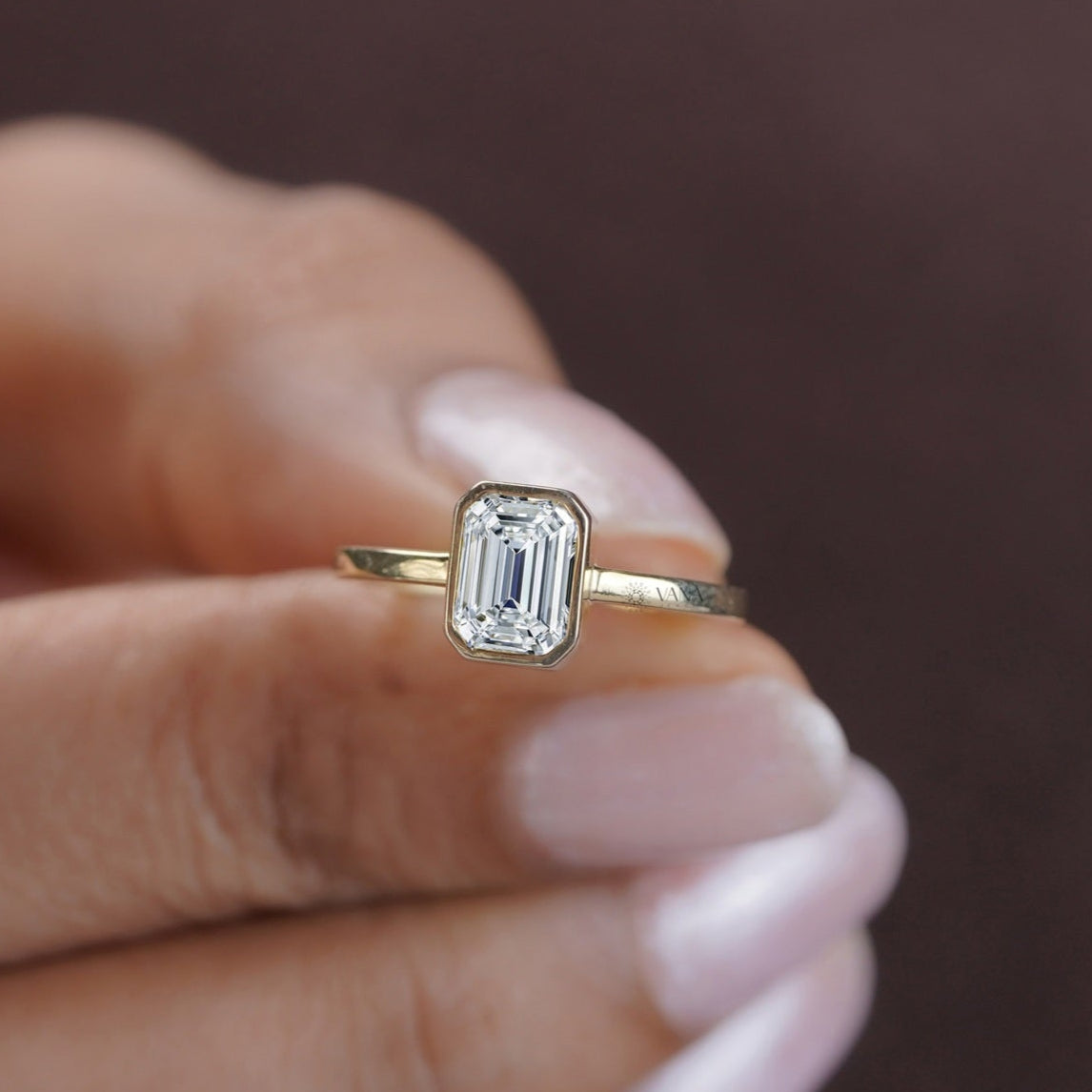 Trendy and timeless emerald moissanite ring in modern yellow gold bezel setting