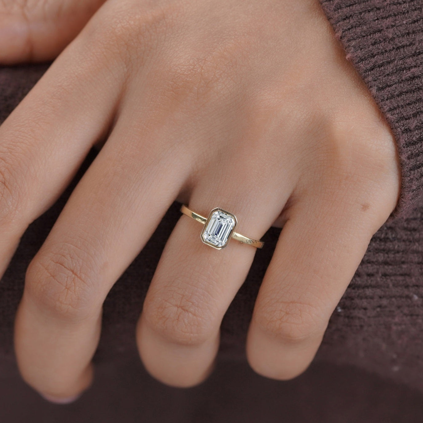 Elegant emerald cut moissanite solitaire engagement ring with bezel setting in 14K yellow gold