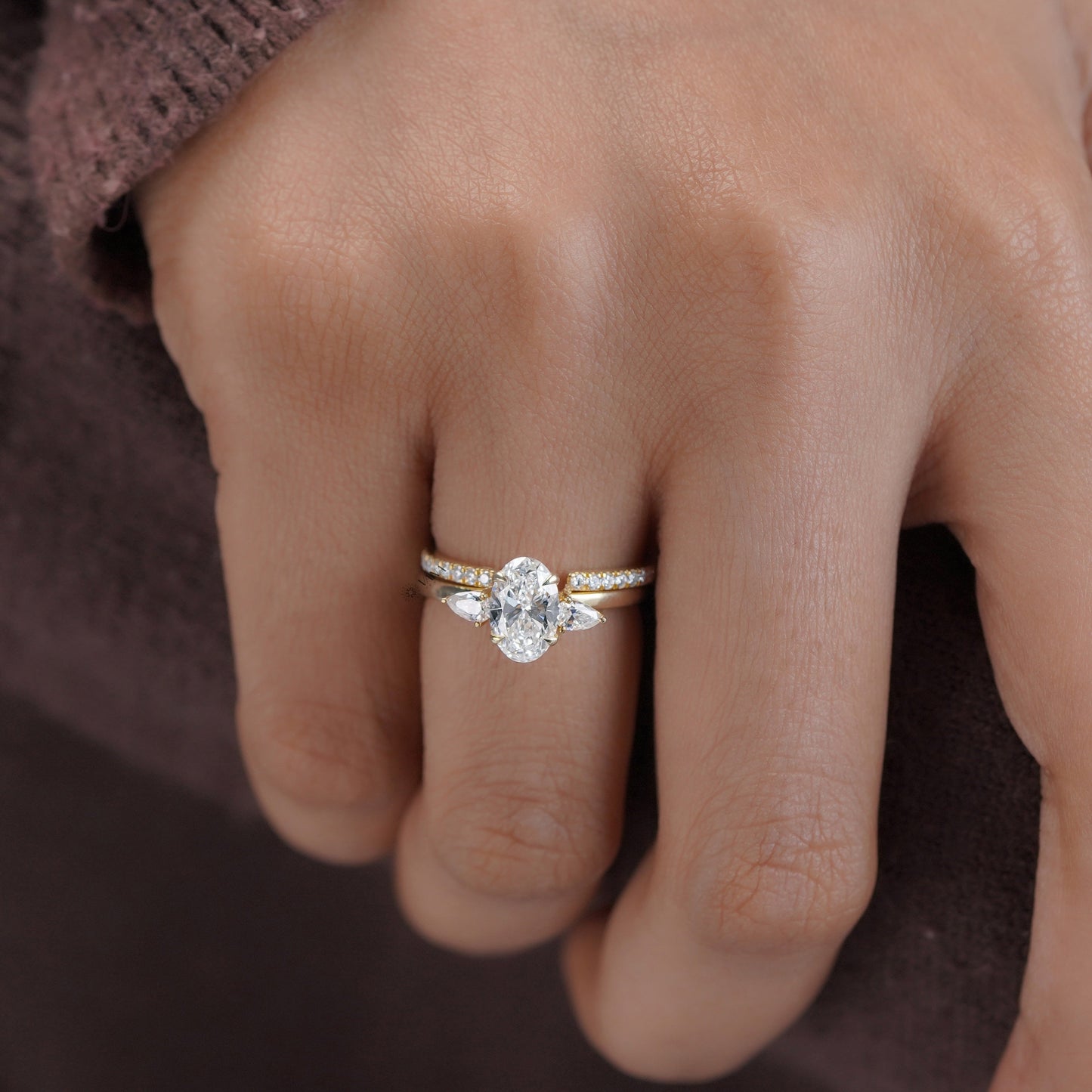 Close-up of a hand wearing a diamond ring on a dark background