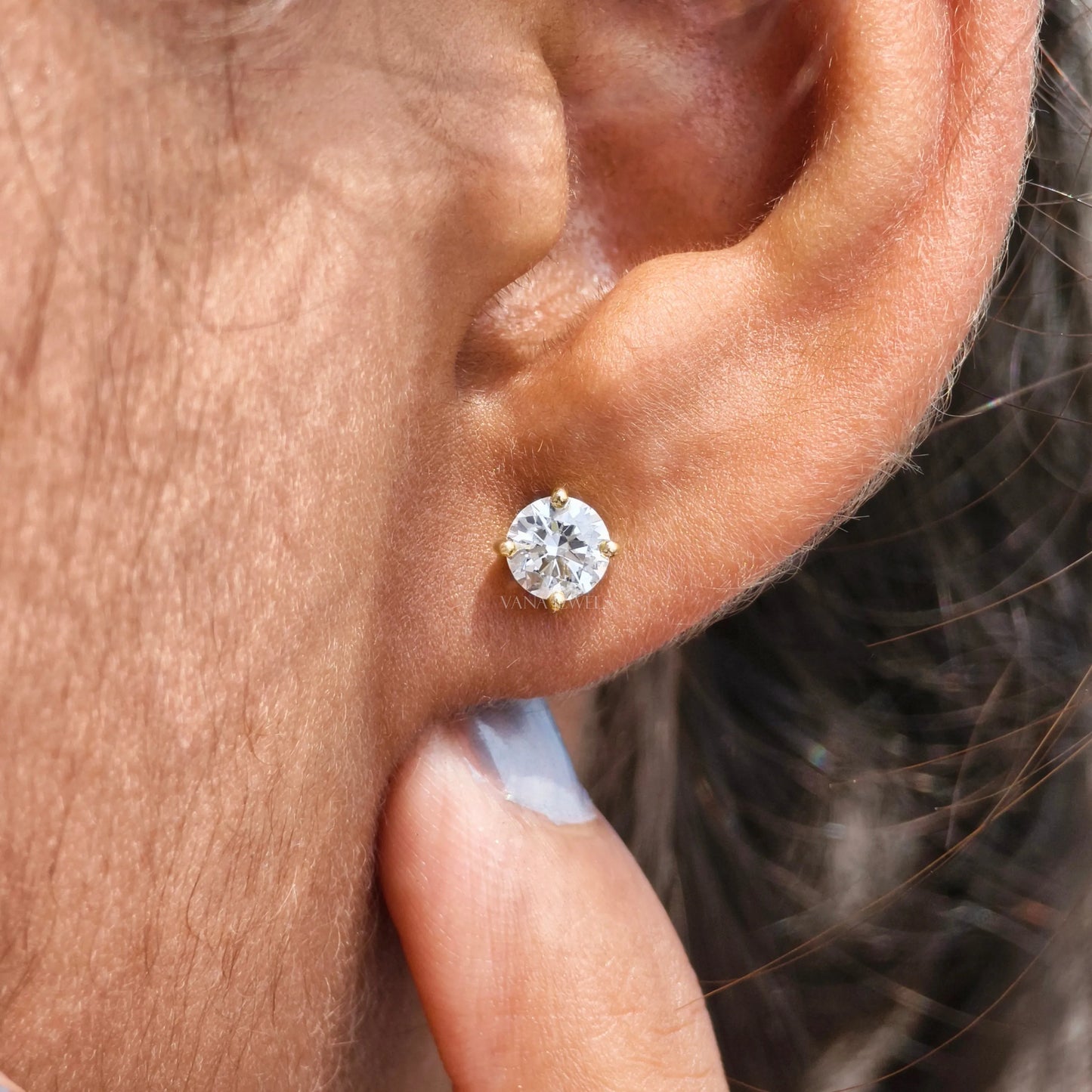 A person wearing a screw back round Moissanite wedding earring in their left ear.