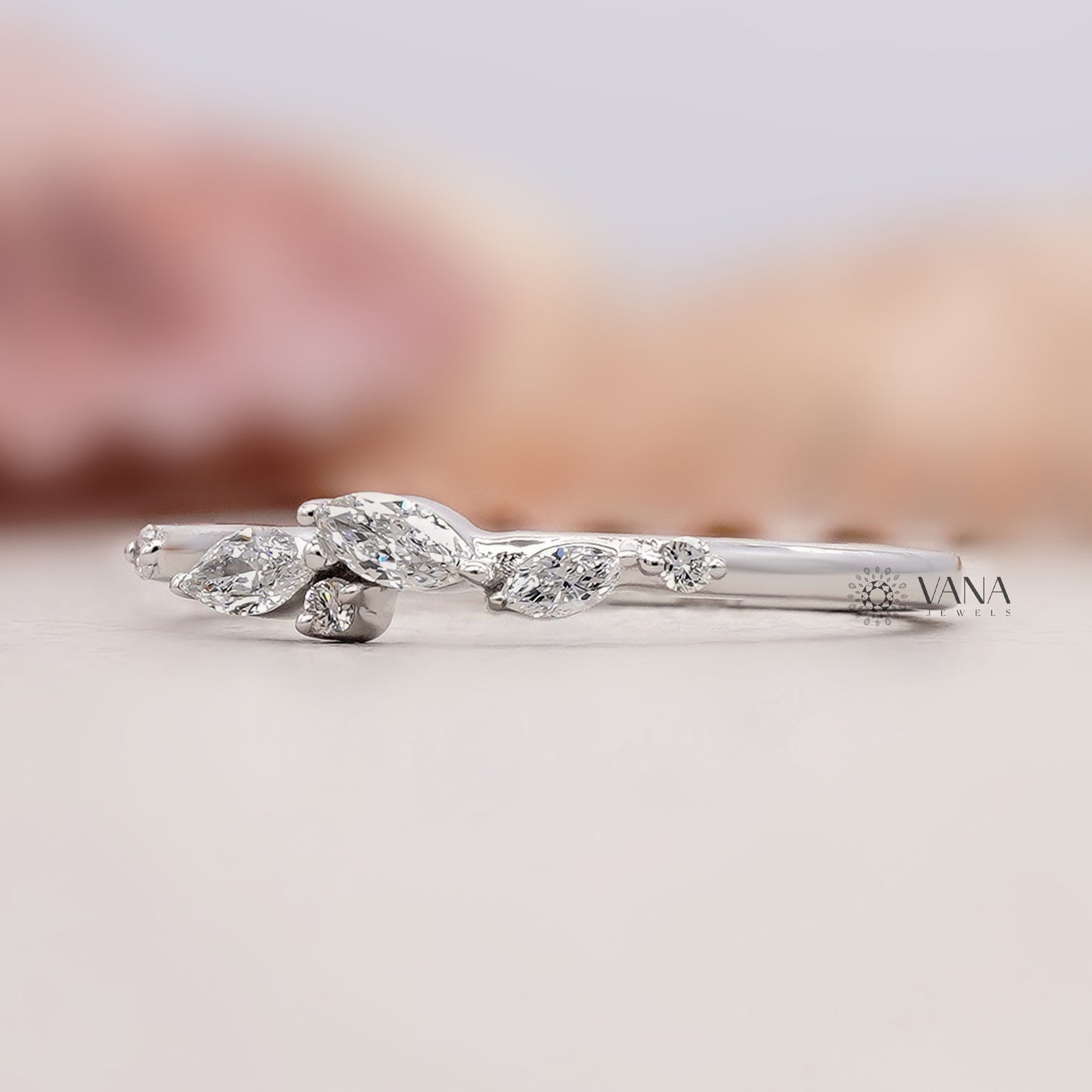 Silver ring with marquise-shaped diamonds on a light background
