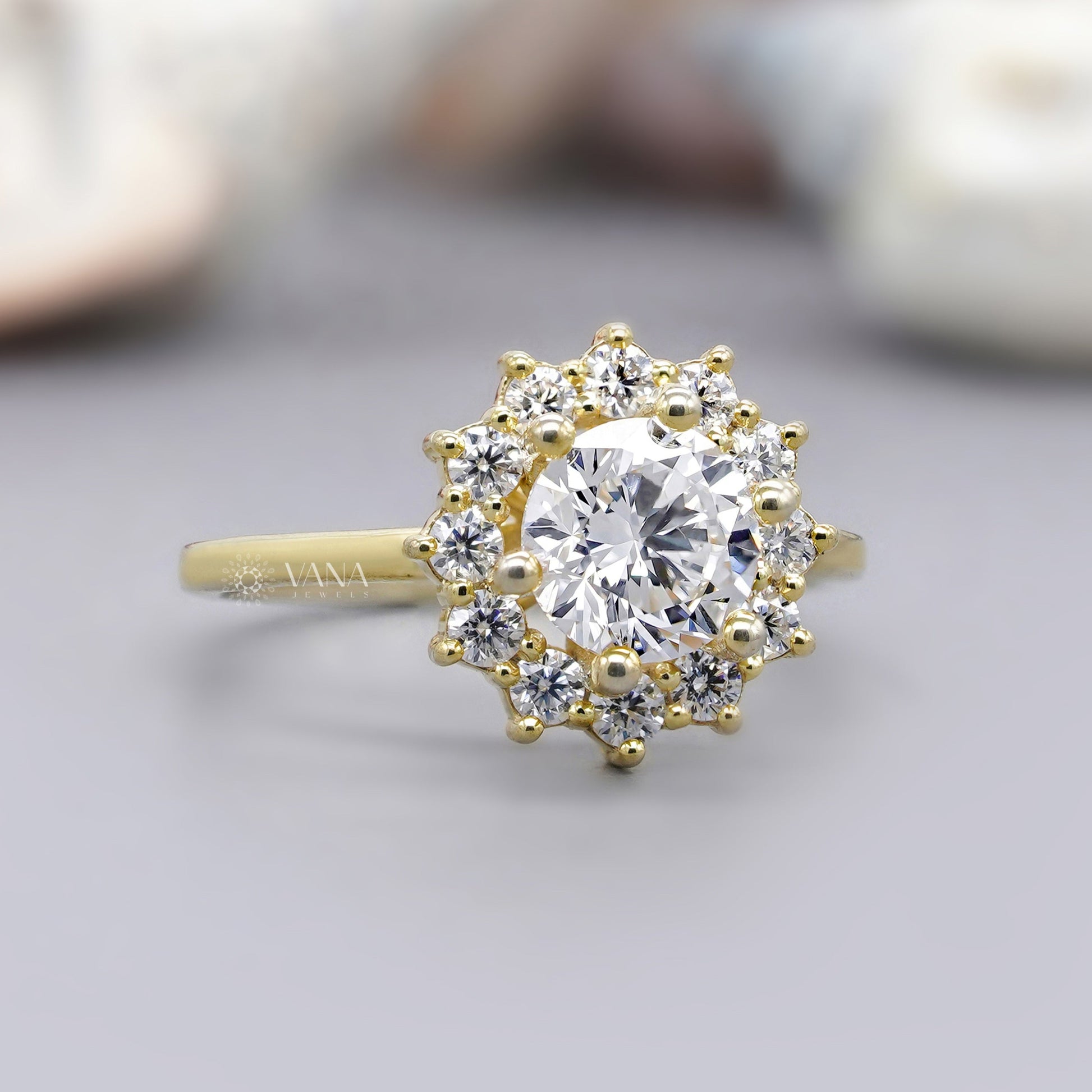 Gold ring with a large central diamond and smaller diamonds around on a light background