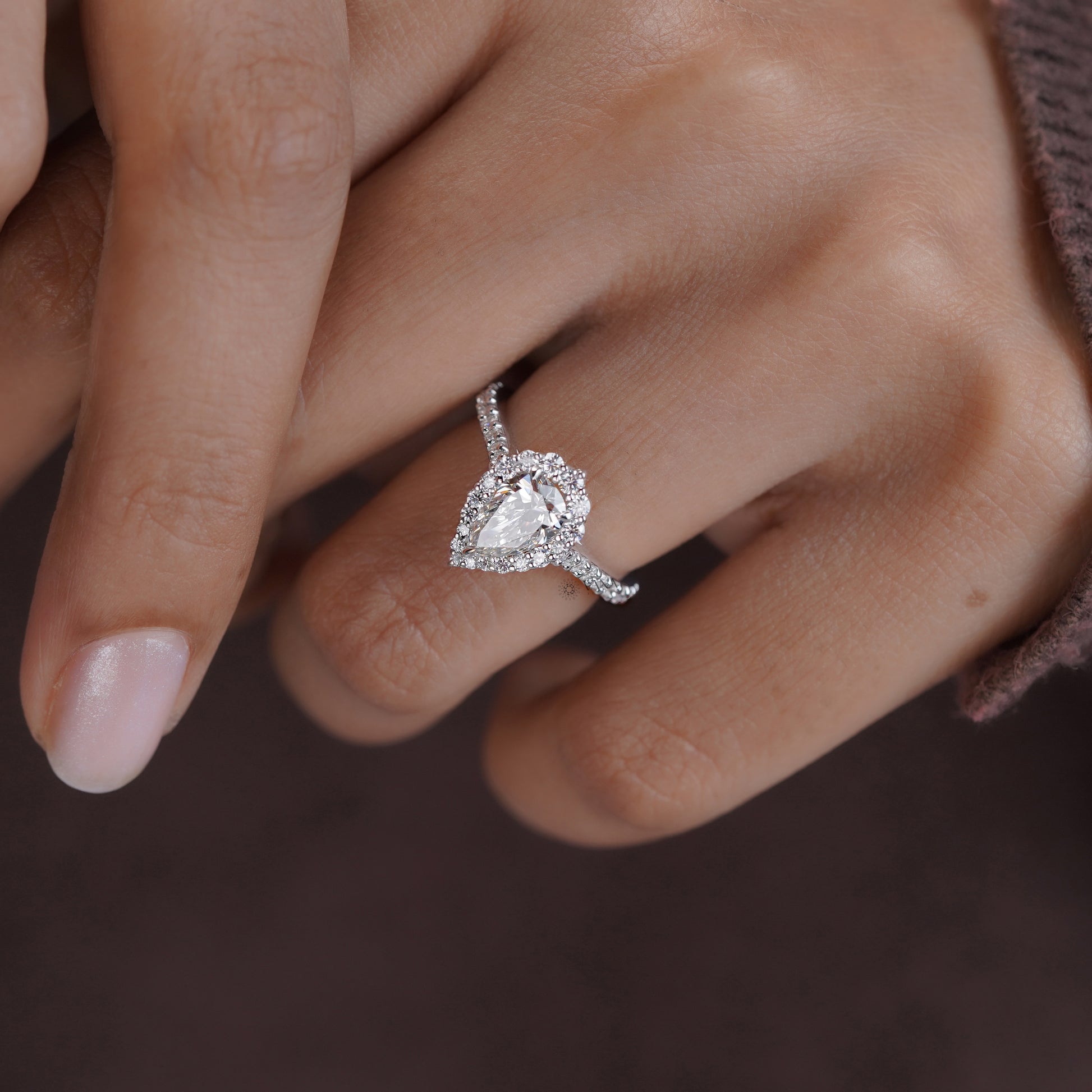 Side view of pear cut moissanite halo ring with brilliant pave band